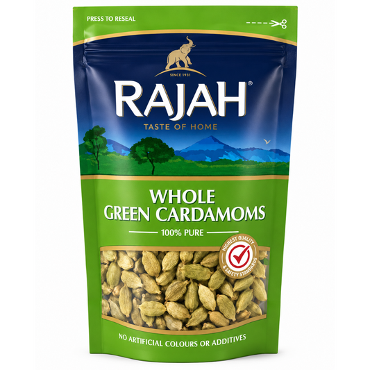 A stand-up pouch of Rajah Whole Green Cardamoms on a plain white background. The packaging is green and dark blue with a scenic landscape illustration, a clear window showing the whole green cardamoms inside, and the Rajah brand logo at the top.