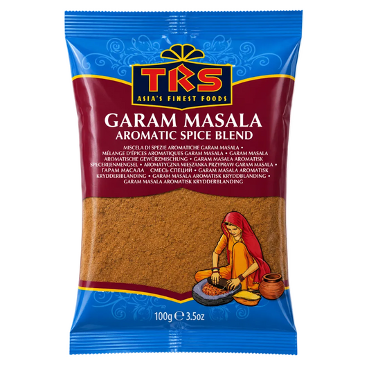 A 100g package of TKS Garam Masala aromatic spice blend. The packaging features a blue top and bottom border, a dark red central band with the brand name 'TRS' in gold and red, and a clear window showing the brown spice blend inside.